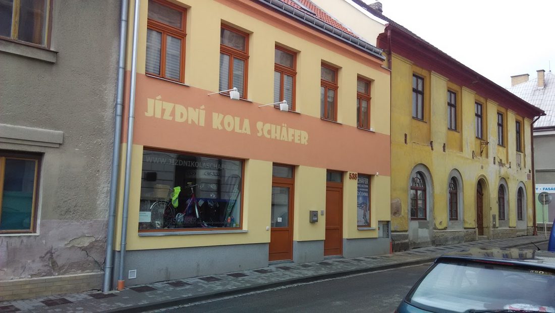 Oranžový dům s nápisem Jízdní kola Schafer a výlohou prodejny